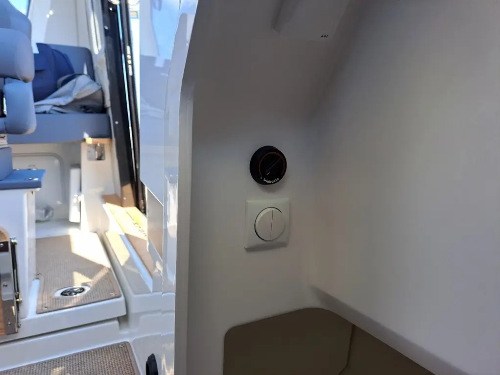 Control panel in a boat, featuring a "Webasto" dial and a switch, with a seating area visible in the background.